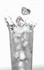Cubitos de hielo cayendo en un vaso de agua - foto de stock