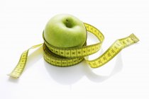 Green apple with tape measure — Stock Photo