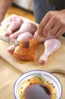 Koch bürstet Hühnerschenkel mit Marinade — Stockfoto