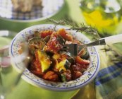 Calabacín y ragú de tomate con cebolla, ajo y romero en plato con tenedor - foto de stock