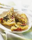 Courgette and pepper frittata on white plate over towel — Stock Photo