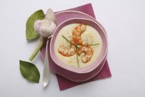 Garlic cream soup with prawns in pink plate over towel — Stock Photo