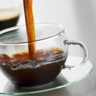 Наливание кофе в стеклянную чашку — стоковое фото