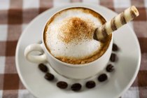 Xícara de cappuccino com rolos de bolacha — Fotografia de Stock
