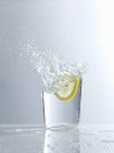 Lasciando cadere la fetta di limone nel bicchiere d'acqua — Foto stock