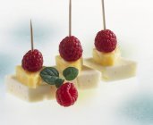 Cheese and raspberries on cocktail sticks — Stock Photo