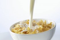 Наливаємо молоко на кукурудзяні пластівці — стокове фото