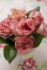 Vista elevada de rosa cortar rosas e folhas em vaso — Fotografia de Stock