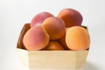 Several apricots in woodchip basket — Stock Photo
