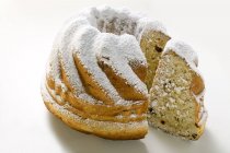 Closeup view of cut Gugelhupf with icing sugar on white surface — Stock Photo