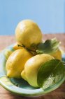 Лимоны с листьями на тарелке — стоковое фото
