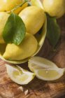 Спелые лимоны с клиньями и листьями — стоковое фото
