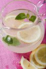 Lemonade in glass jug with mint — Stock Photo