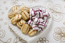 Sweets on heart-shaped plate — Stock Photo