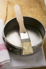 Vue rapprochée du pinceau à pâtisserie avec beurre sur moule à pâtisserie — Photo de stock