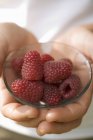 Human hands holding bowl of raspberries — Stock Photo