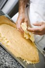 Cropped tilted view of man trimming biscuit base — Stock Photo