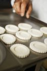 Closeup view of hand arranging tart cases on baking tray — Stock Photo