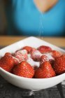 Sprinkling sugar on strawberries — Stock Photo