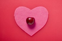 Kirsche auf rosa Stoff Herz — Stockfoto