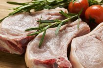 Raw pork chops with rosemary and tomatoes — Stock Photo