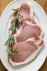 Raw pork chops with rosemary — Stock Photo