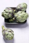 Fresh artichokes in bowl — Stock Photo
