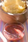 Vista de primer plano de salsa de tomate con chips de tortilla - foto de stock