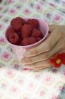 Female hand holding beaker with raspberries — Stock Photo