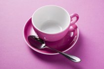 Vista close-up de xícara de café rosa com colher no pires — Fotografia de Stock