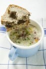 Sopa de cebada con tocino y pan en cazuela azul sobre toalla - foto de stock