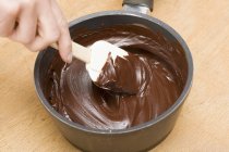Menschliche Hand rührt geschmolzene Schokolade an — Stockfoto