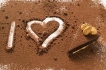 Closeup view of I letter and heart written on chocolate powder by tart — Stock Photo