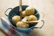 Fresh potatoes and peeler — Stock Photo