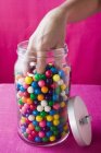 Обрезанный вид руки, хватая конфеты из сладкой банки — стоковое фото