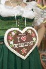 Cropped view of woman in national dress with Lebkuchen heart — Stock Photo