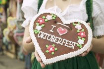 Cropped view of woman in national dress holding Lebkuchen heart — Stock Photo