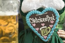 Vista recortada de la mujer con el corazón Lebkuchen en Oktoberfest - foto de stock