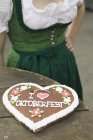 Lebkuchen heart on rustic table with woman on background — Stock Photo