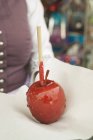 Closeup cropped view of woman with toffee apple on paper — Stock Photo