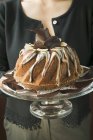 Vue rapprochée de la femme servant Gugelhupf avec du chocolat et de la crème vanille — Photo de stock