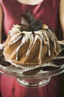 Closeup cropped view of woman serving Gugelhupf with chocolate and vanilla cream — Stock Photo