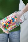 Обрізаний вид людини, що бере кольорові кульки жувальної гумки з банки — стокове фото