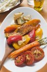 Roasted vegetables on white platter with wooden spoon — Stock Photo