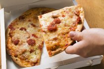 Hand taking slice of pizza — Stock Photo