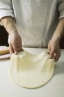 Шеф-повар растягивает тесто для пиццы — стоковое фото