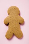 Крупним планом вид одного печива у формі імбирного чоловіка на рожевій поверхні — стокове фото