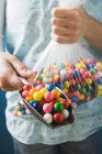 Cropped view of person holding plastic bag and scoop wit bubble gum balls — Stock Photo