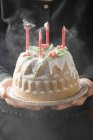 Cropped view of woman serving walnut Gugelhupf with four blown-out candles — Stock Photo