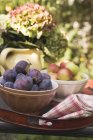 Plums and apples in bowls — Stock Photo